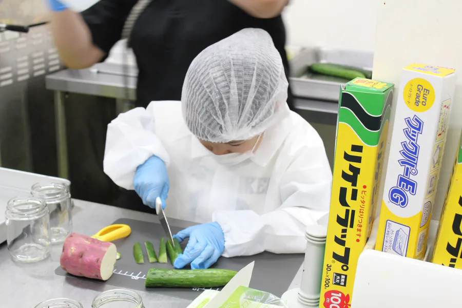 白衣に着替えて食品加工に挑戦する子ども