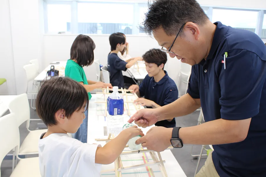 社員の方に教わりながら木材の橋づくりに挑戦する子ども