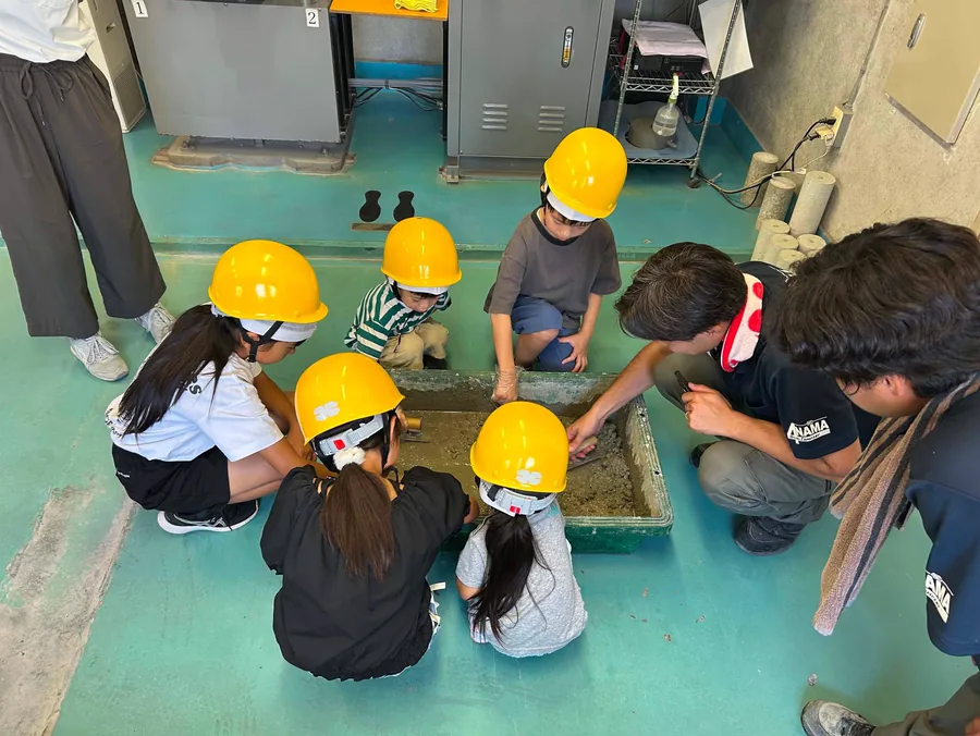 ヘルメットをかぶって現場をのぞきこむ子どもたち