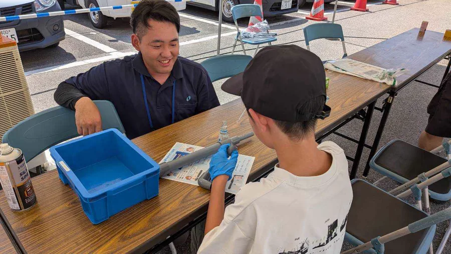 笑顔で子どもに作業を教える企業スタッフ